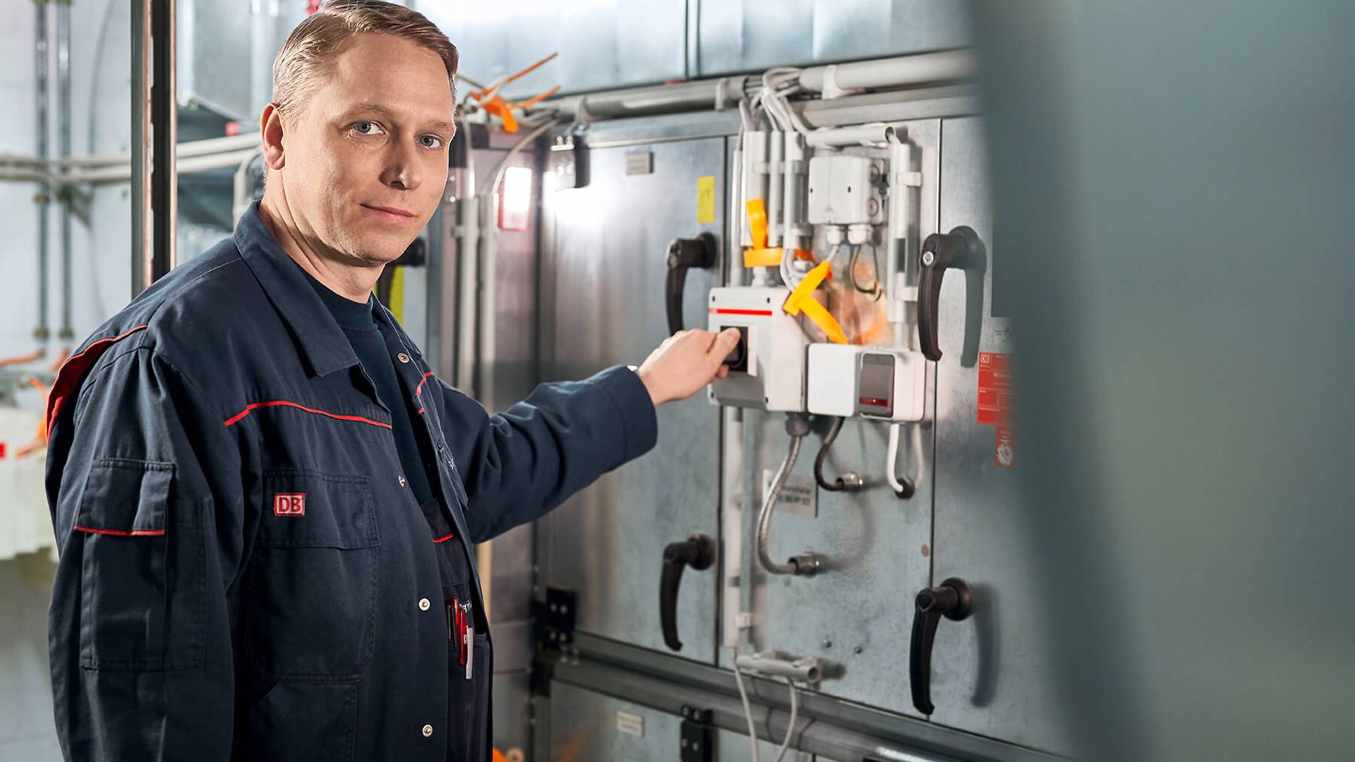 Ein Mann lächelt in die Kamera. Gleichzeitig bedient er die Maschine hinter ihm.