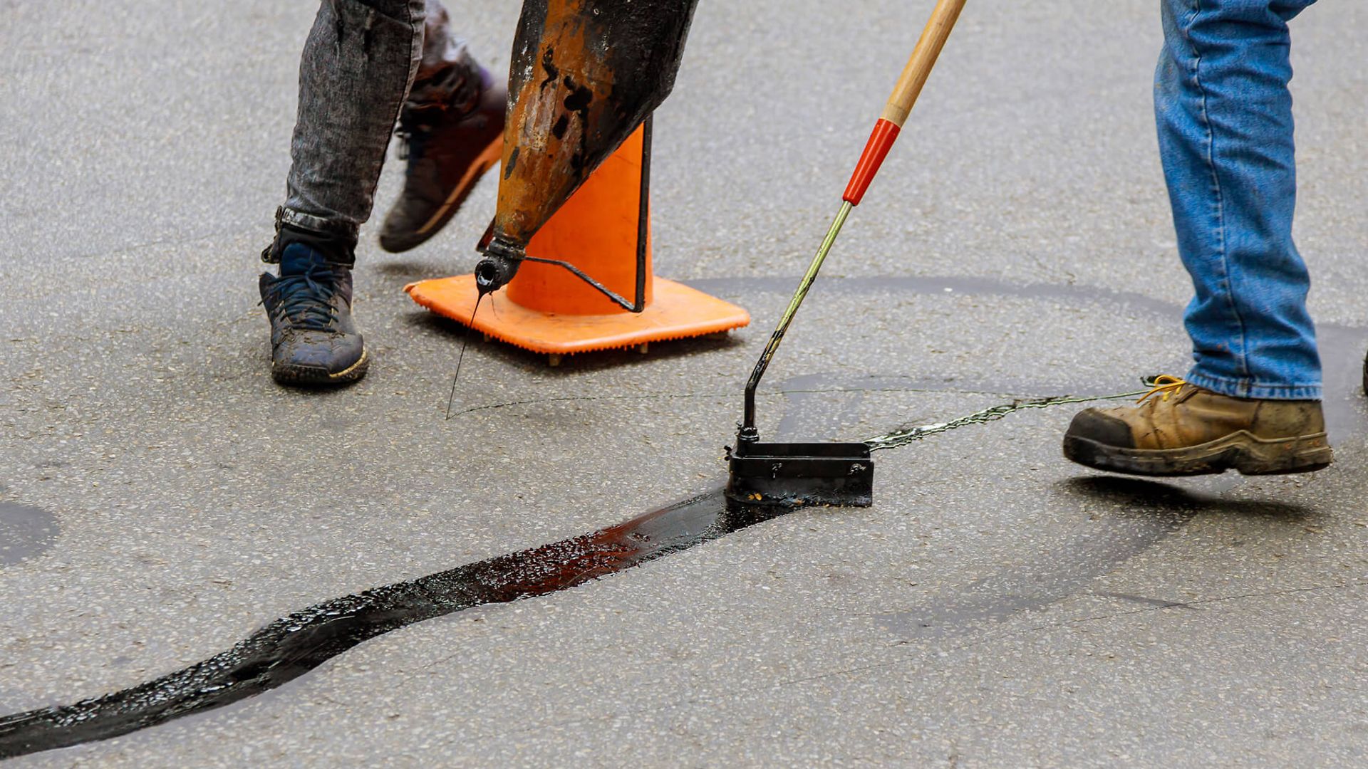 Risse der Straße werden mit Teer aufgefüllt.