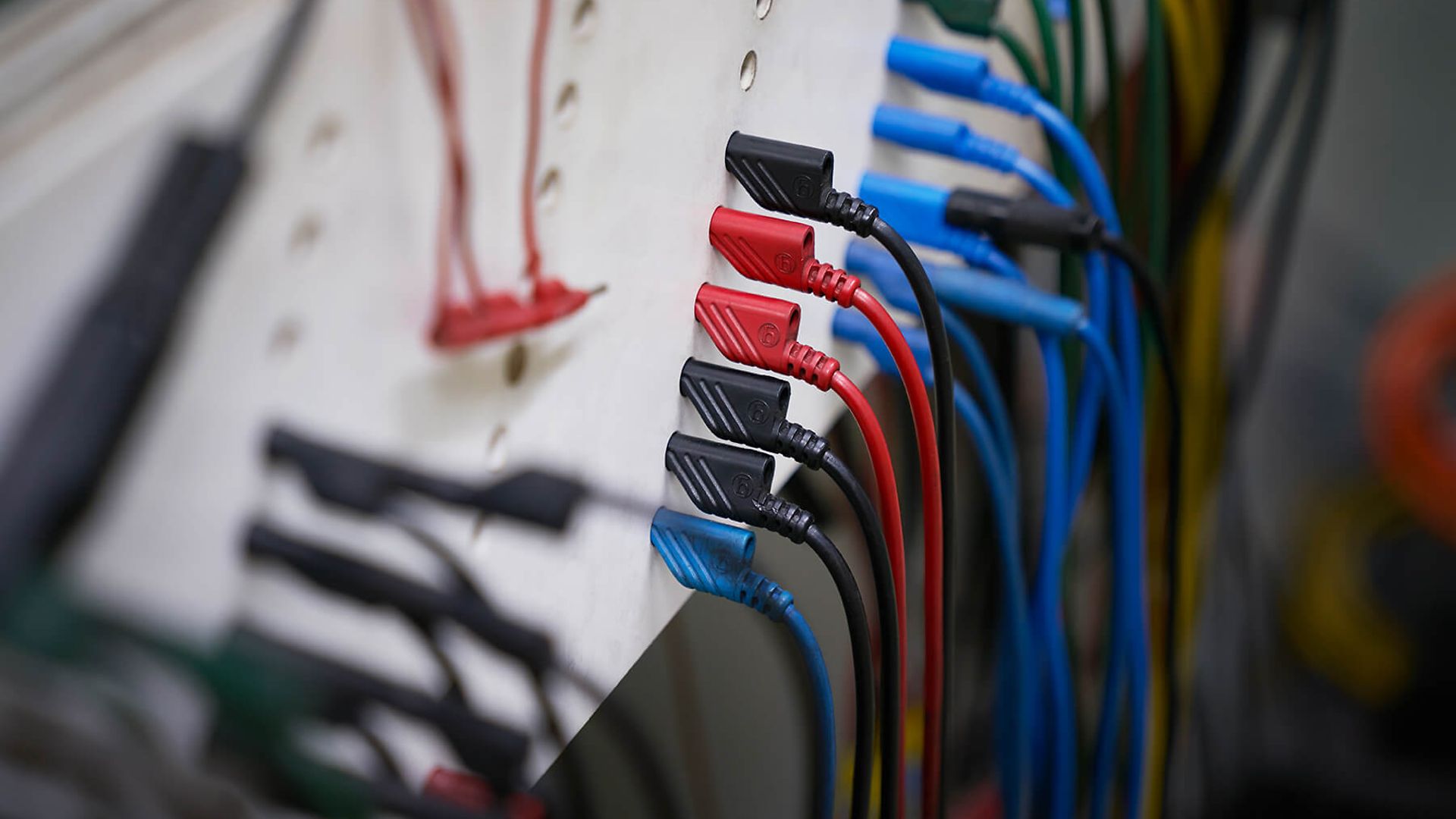 Nahaufnahme von schwarzen, roten und blauen Kabeln, die in eine Maschine führen.