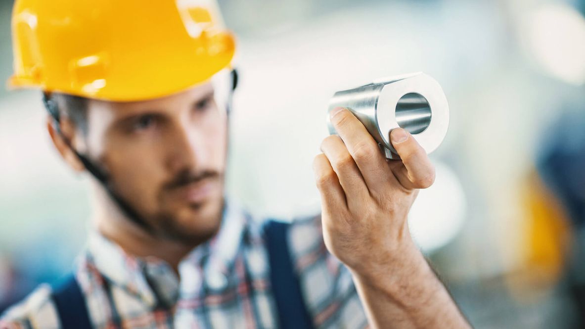 Ein Mann schaut ein Metallstück intensiv an.