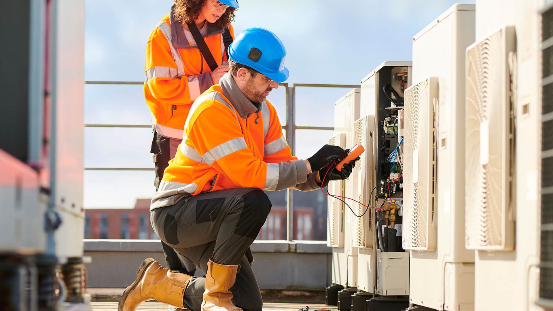 Zwei Personen knien auf dem Dach. Der vordere Mann liest mit einem Gerät etwas ab.
