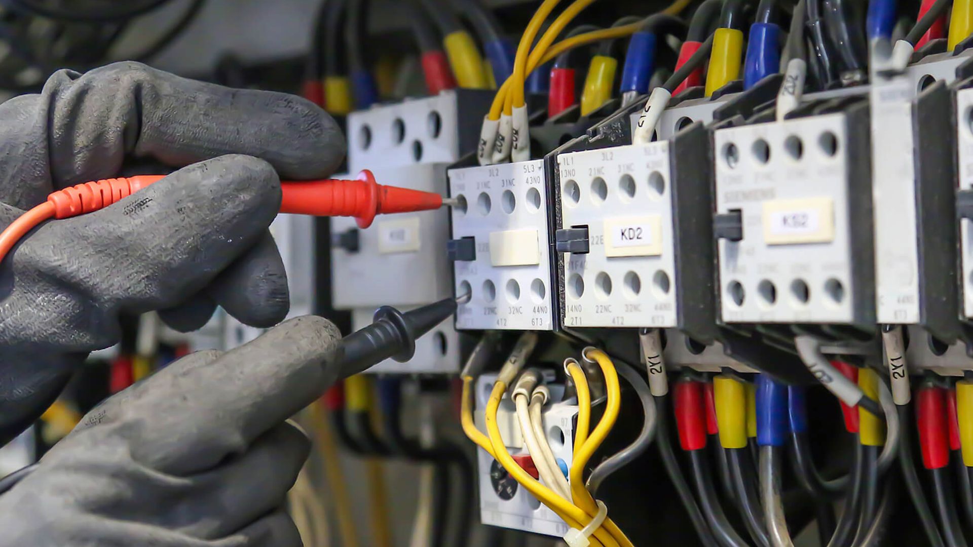 Nahaufnahme eines Schalt- oder Sicherungskastens. An Eine Verbindung werden gerade die zwei Fühler eines Messgerätes gehalten.