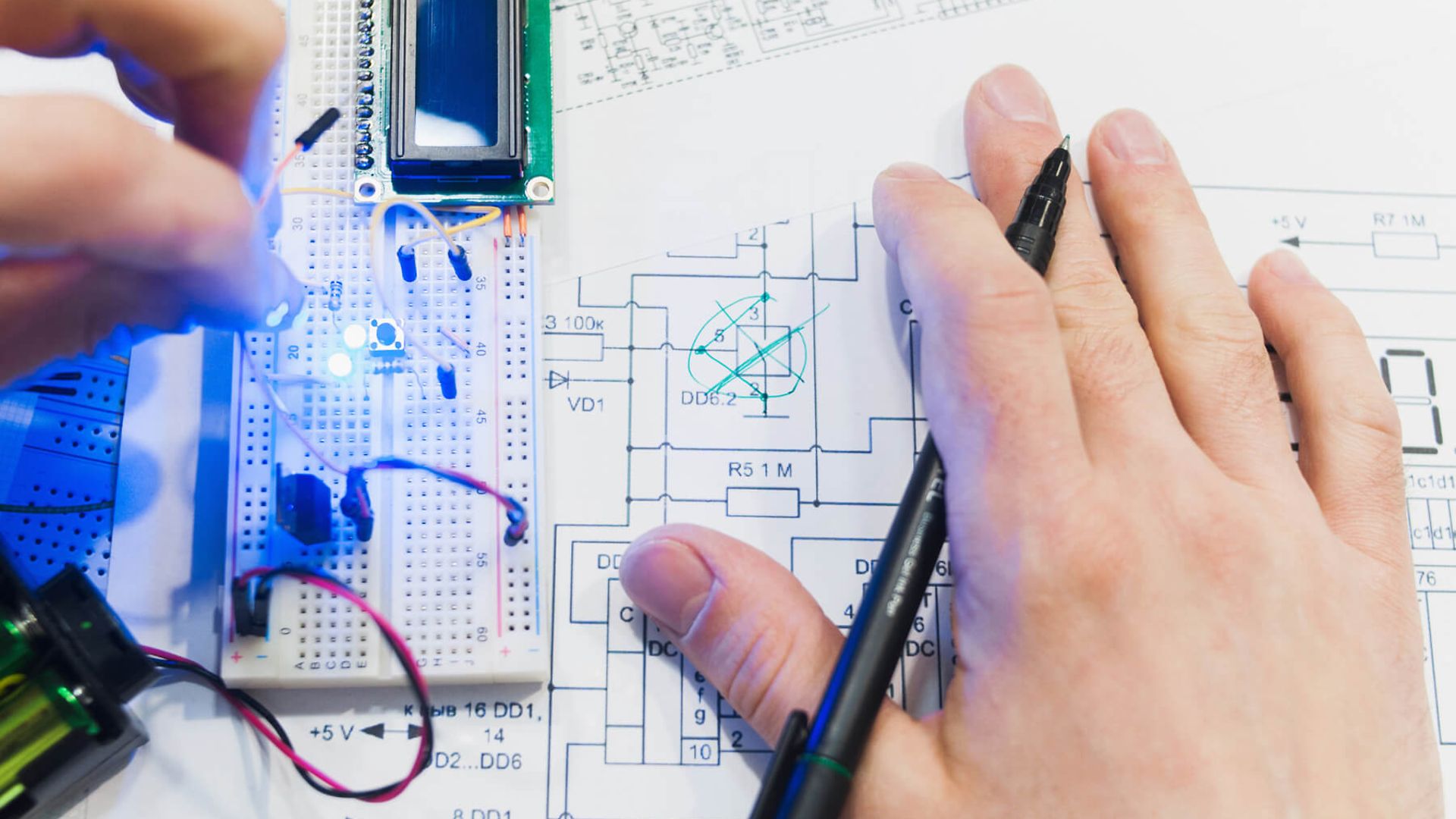 Eine Hand mit einem Stift in der Hand ist über einer Skizze zu sehen.