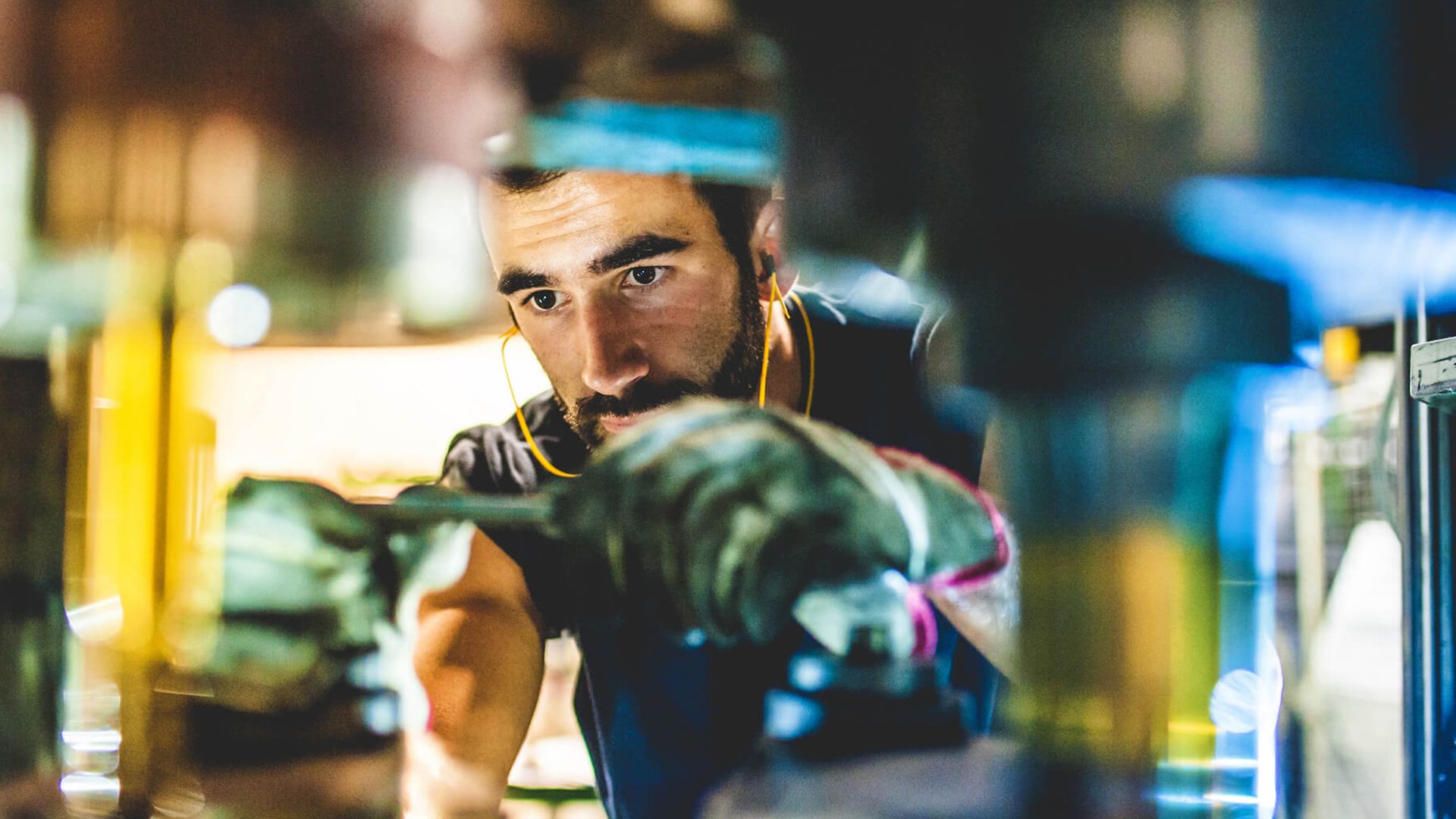 Ein Mann repariert eine Maschine. Der Blickwinkel ist vom inneren der Maschine nach außen.