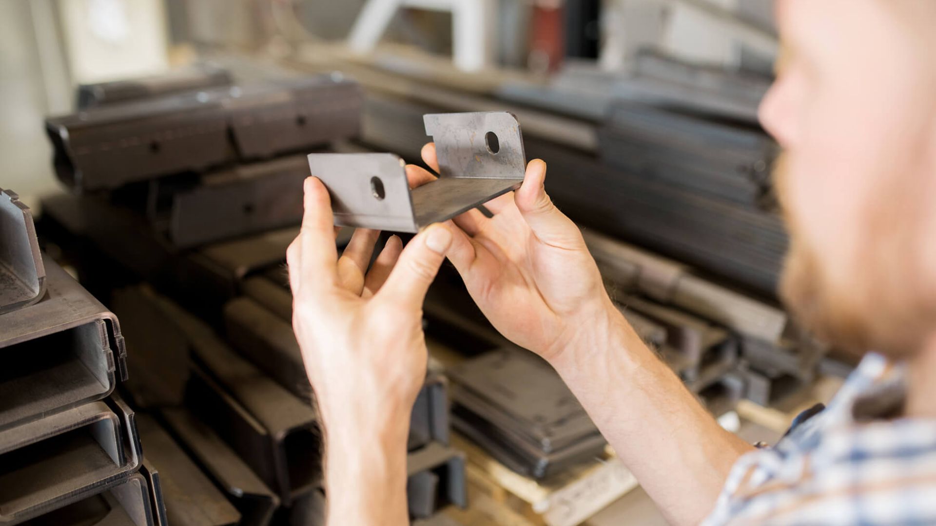 Ein Mann hat ein Metallstück in der Hand und betrachtet es.