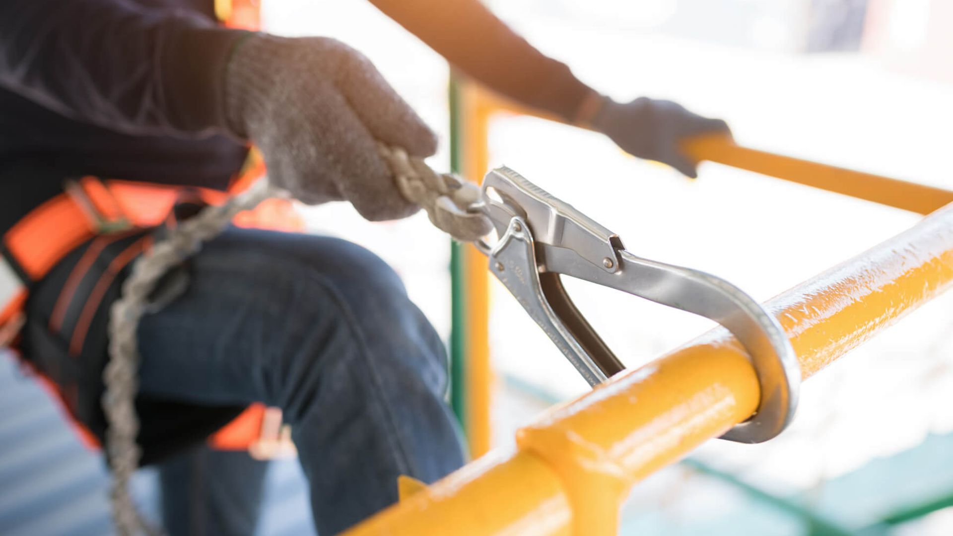 Eine Person ist über Gurt und Karabiner an einem Geländer gesichert.