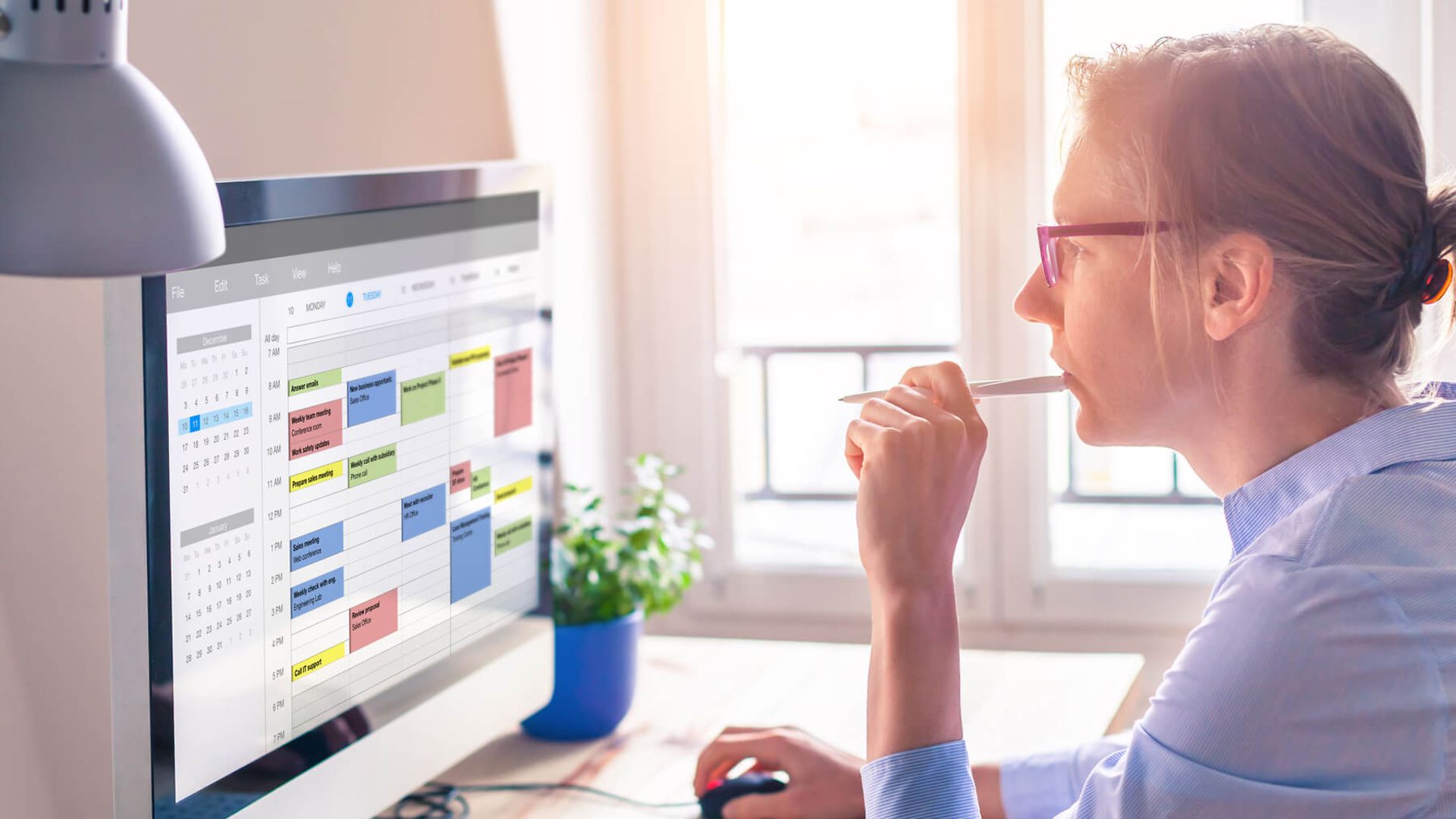 Eine Frau hat den Blick auf den Bildschirm gerichtet. Auf dem Bildschirm ist ein Terminplan zu sehen.