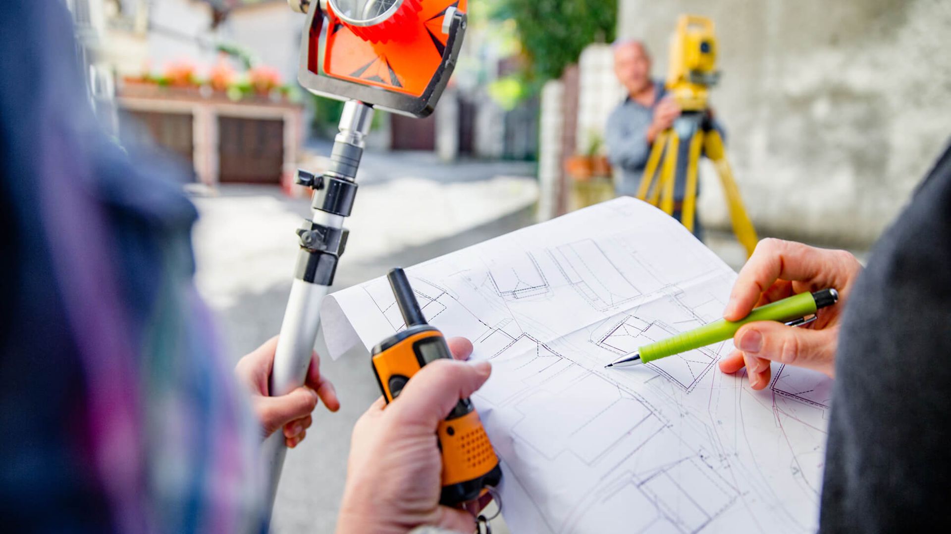 Zwei Personen gehen einen Plan durch. Die eine Person zeigt mit einem Stift etwas im Plan und hält ein Funkgerät.