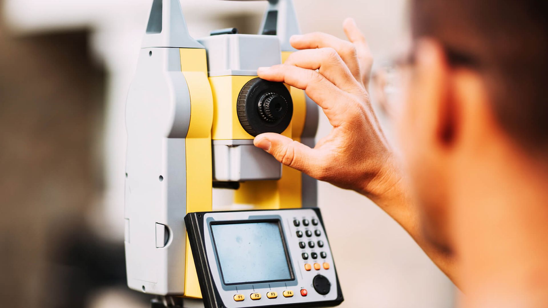 Eine Person stellt ein Messgerät ein. Das Messgerät steht im Fokus, die Person ist nur angedeutet zu erkennen.