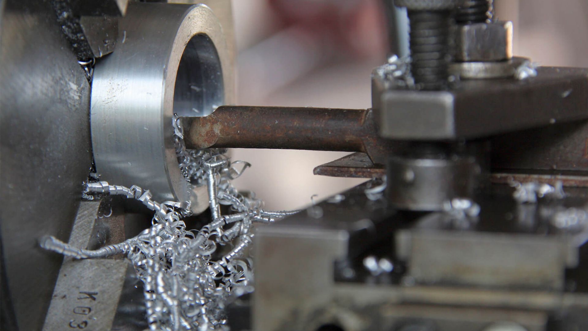 Nahaufnahme einer Maschine, die Metal fräst. Dabei entstehen Späne aus Metall.