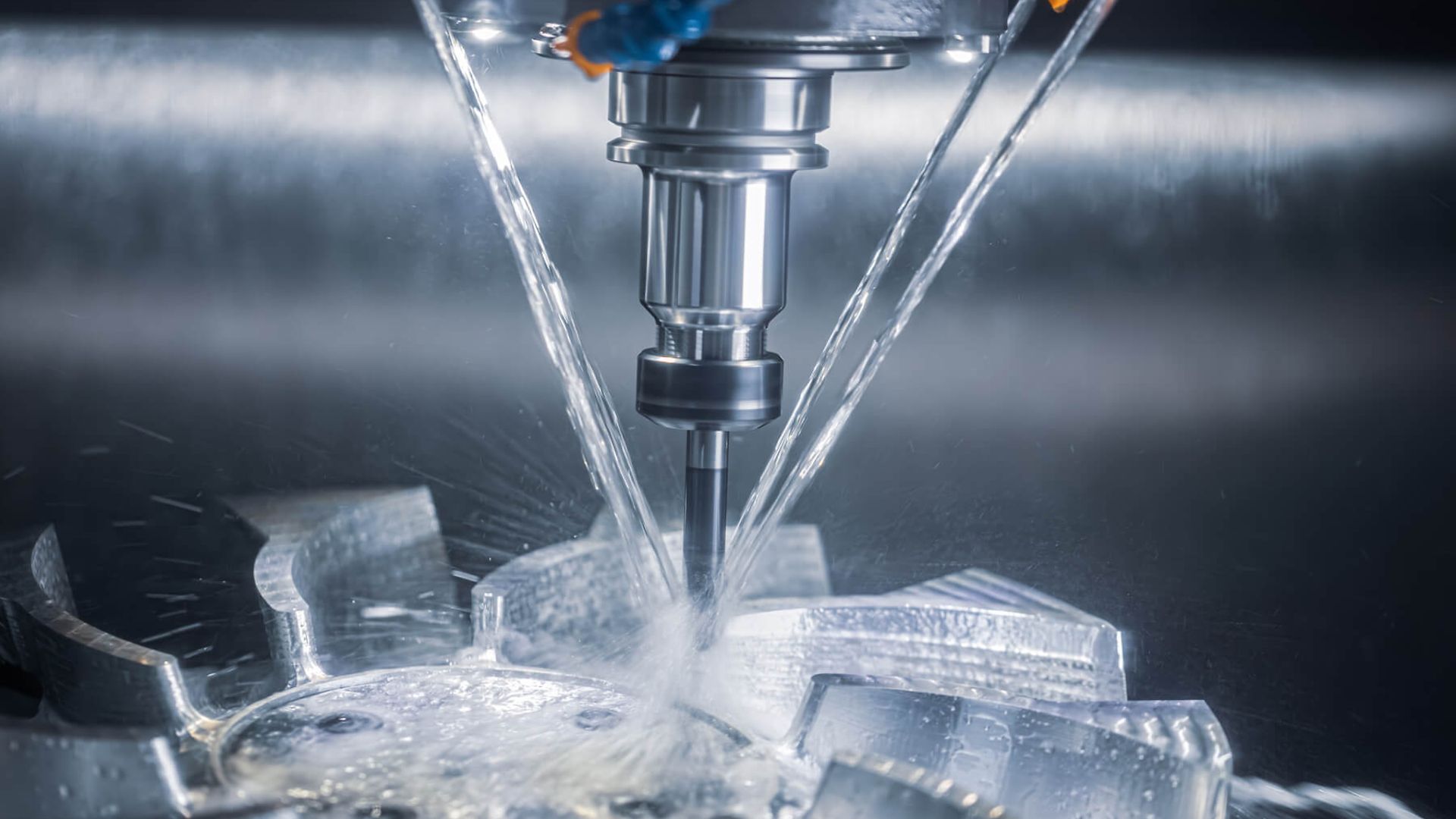 Nahaufnahme eines feinen Bohrkopfes einer CNC Maschine, der sich in Metall arbeitet und mit Wasser gekühlt wird.